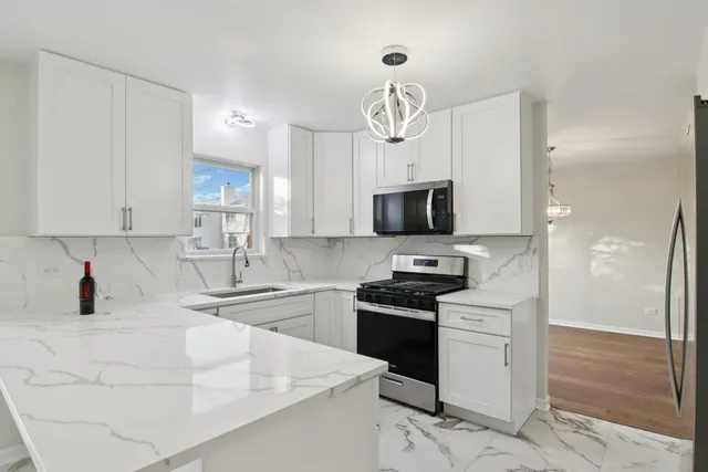 a kitchen with granite countertop a refrigerator stove and white cabinets