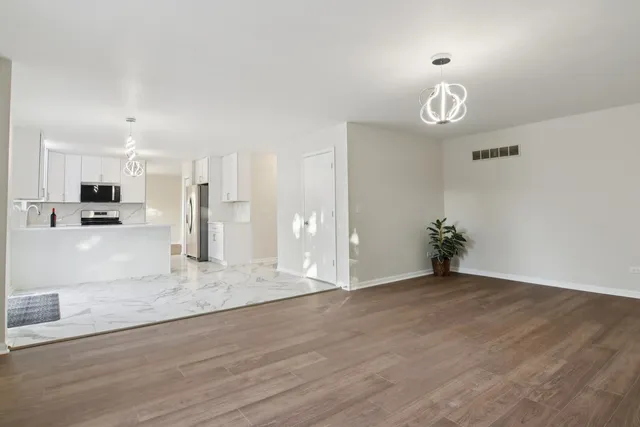 a kitchen with granite countertop a refrigerator and white cabinets