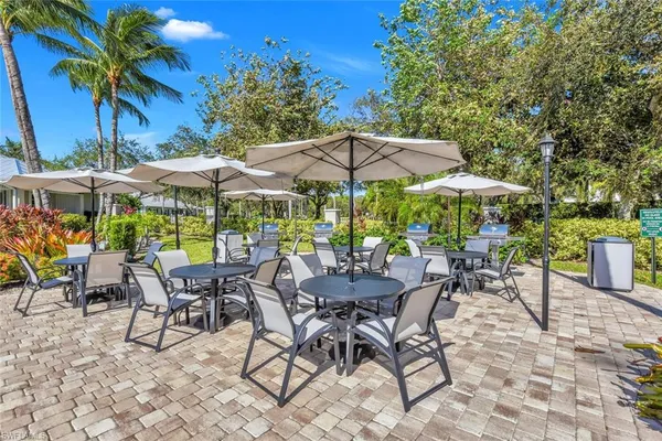a view of patio with chairs and tables with an umbrella