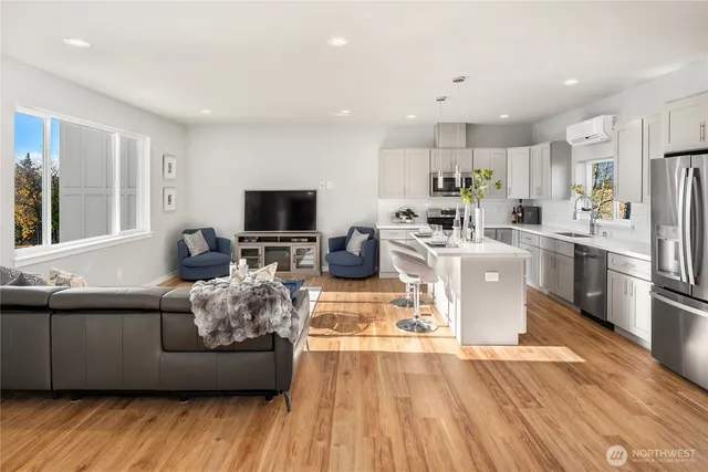a living room with stainless steel appliances furniture and a kitchen view