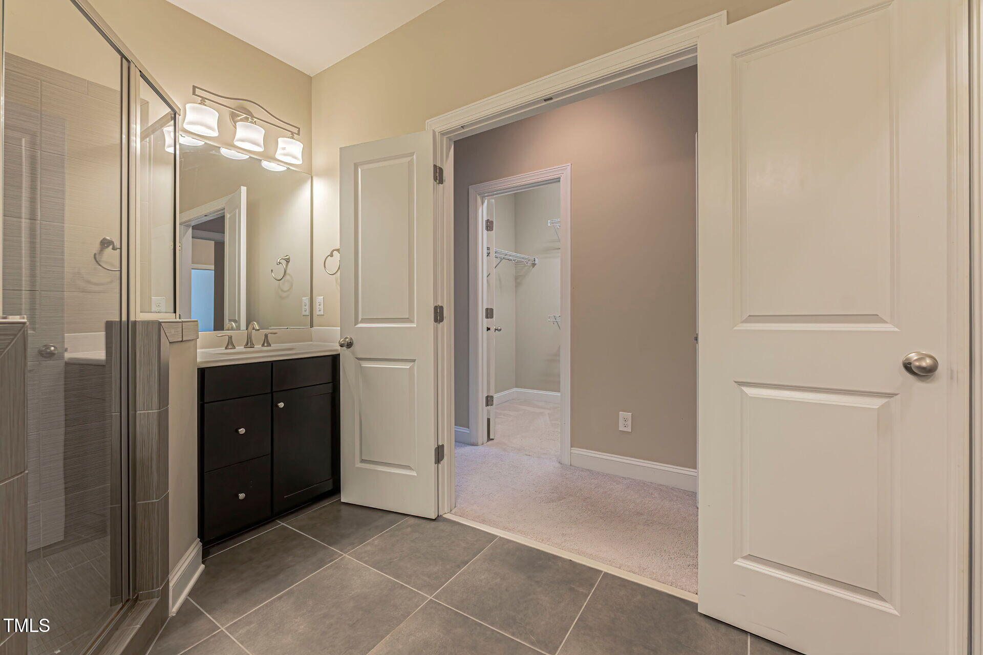 3606 Winifred Way Raleigh, NC 27609 - Photo 31 of 45 a bathroom with a mirror a double vanity sink and glass door