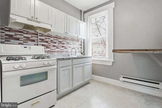 a kitchen with granite countertop white cabinets and white appliances