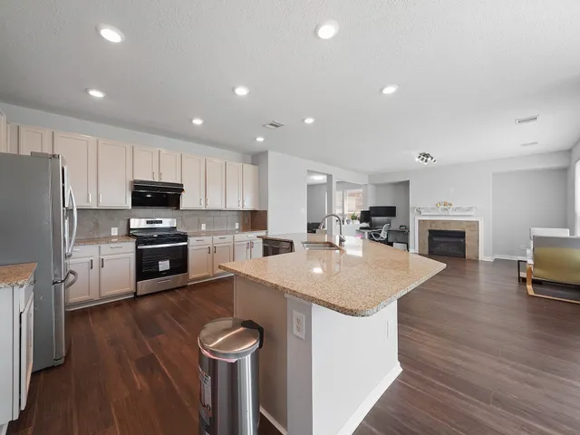 a kitchen with granite countertop a sink a counter top space stainless steel appliances and cabinets