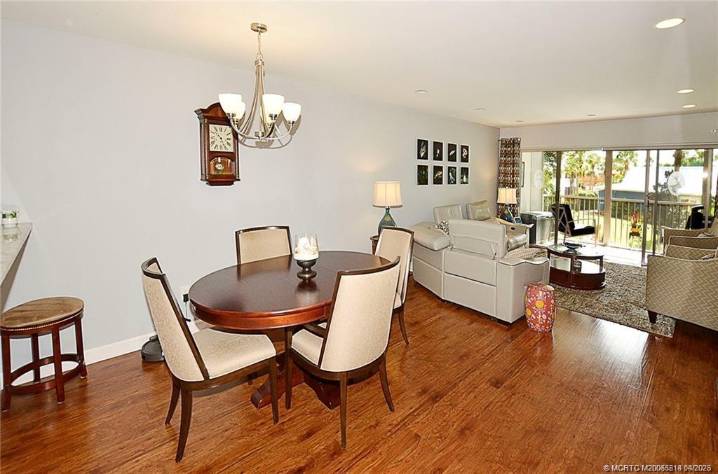 1854 Southwest Palm City Road, Unit 203 Stuart, FL 34994 - Photo 17 of 38 a dining room with furniture a chandelier and wooden floor