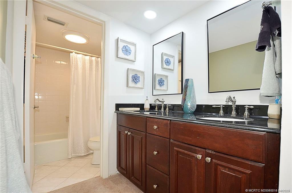 1854 Southwest Palm City Road, Unit 203 Stuart, FL 34994 - Photo 18 of 27 Primary bathroom features a dual sink vanity with granite countertops, ample storage, and a separate shower area.