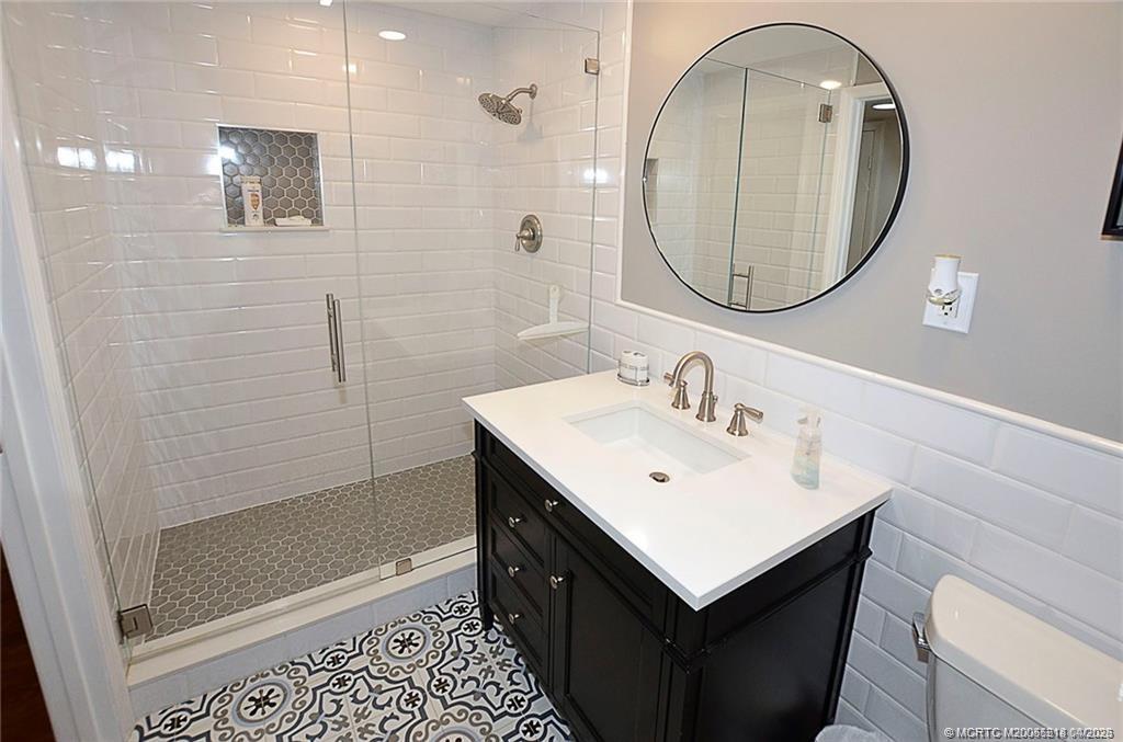 1854 Southwest Palm City Road, Unit 203 Stuart, FL 34994 - Photo 22 of 27 Step into this beautifully renovated bathroom with a sleek glass-enclosed shower, timeless subway tile, and designer finishes that create a fresh, spa-like feel