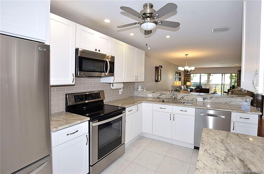 1854 Southwest Palm City Road, Unit 203 Stuart, FL 34994 - Photo 8 of 27 This stunning kitchen is the heart of the home, featuring expansive granite counters, modern white cabinetry, and an open layout that flows seamlessly into the living space and out to the lanai—perfect for entertaining.