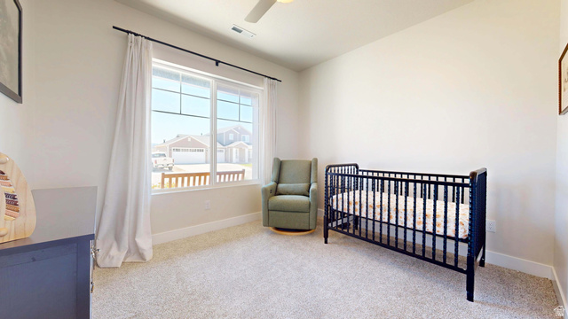 1127 4240 North Enoch, UT 84721 - Photo 30 of 56 Bedroom featuring a nursery area, light carpet, and a ceiling fan
