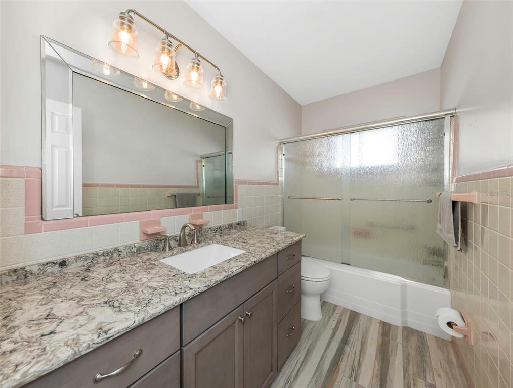 1445 Corey Way South South Pasadena, FL 33707 - Photo 36 of 61 a bathroom with a granite countertop sink a mirror and a shower