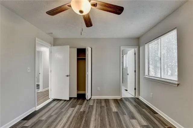 an empty room with windows and ceiling fan
