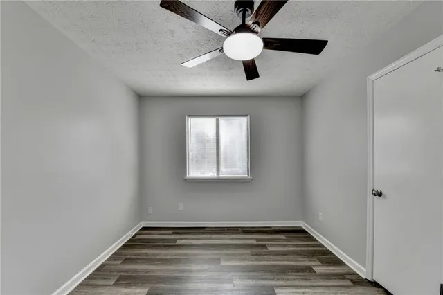 an empty room with wooden floor mirror and windows