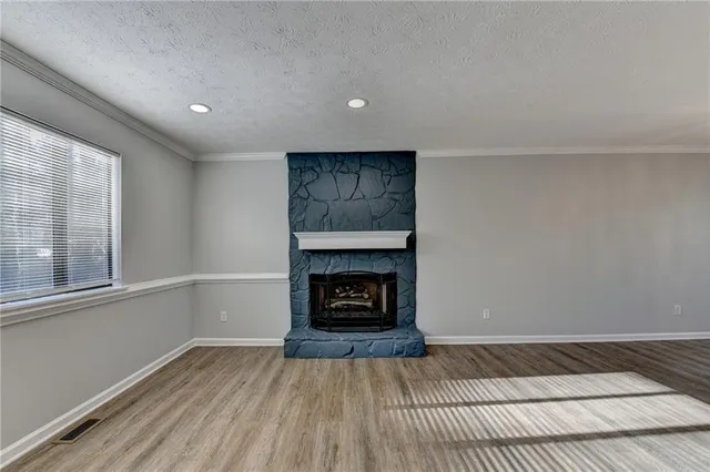 an empty room with wooden floor a fireplace and windows