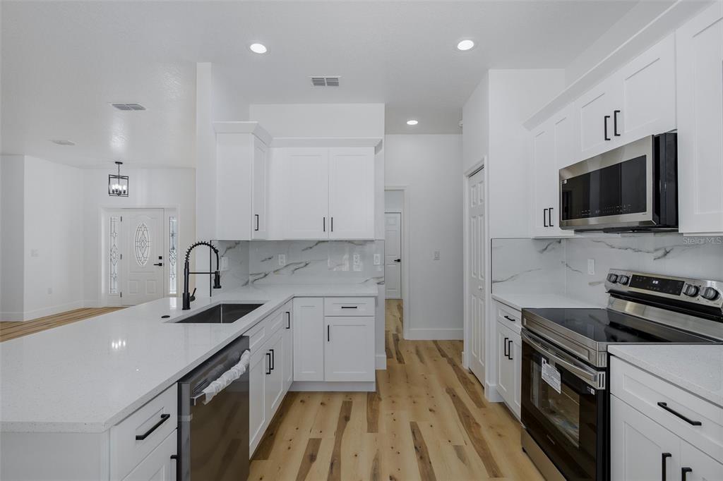11277 Fool Duck Avenue Weeki Wachee, FL 34613 - Photo 10 of 75 a kitchen with a sink stove and microwave