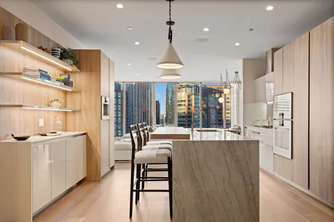 a large kitchen with kitchen island a stove a sink a refrigerator and white cabinets with wooden floor
