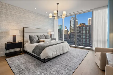 a spacious bedroom with a bed a chandelier and a couch