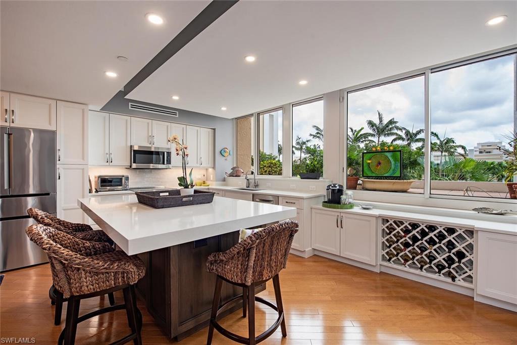 7117 Pelican Bay Boulevard, Unit 206 Naples, FL 34108 - Photo 1 of 35 a kitchen with stainless steel appliances kitchen island granite countertop a sink a stove a refrigerator cabinets and a dining table