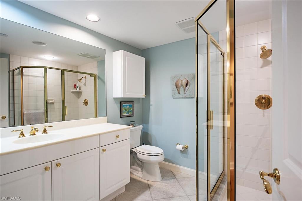 7117 Pelican Bay Boulevard, Unit 206 Naples, FL 34108 - Photo 15 of 35 a bathroom with a double vanity sink toilet mirror and shower