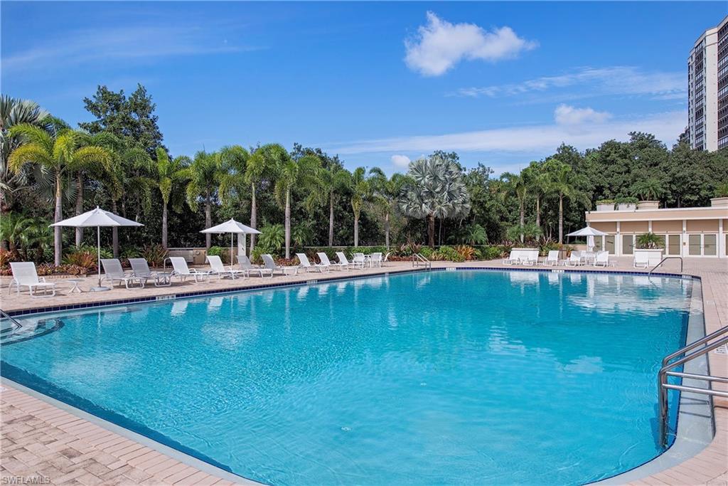 7117 Pelican Bay Boulevard, Unit 206 Naples, FL 34108 - Photo 25 of 35 a view of a swimming pool with a table and chairs