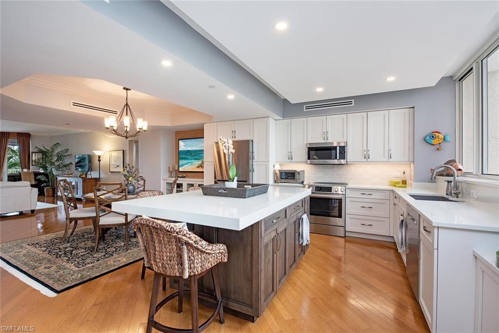7117 Pelican Bay Boulevard, Unit 206 Naples, FL 34108 - Photo 5 of 35 a large kitchen with kitchen island a sink table and chairs