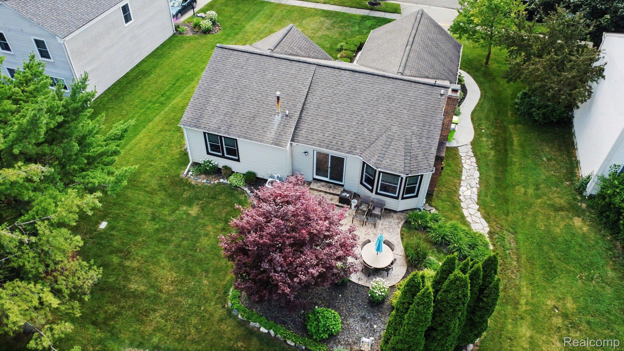 24404 Jamestowne Road Novi, MI 48375 - Photo 26 of 26 Expansive rear yard with a flagstone patio, mature landscaping, and sliding glass doors