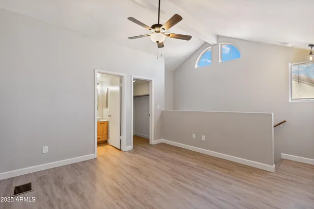 an empty room with wooden floor and ceiling fan