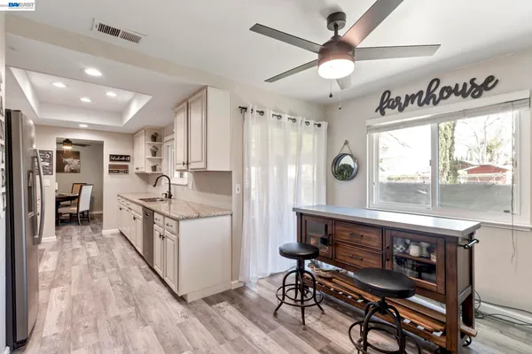 a kitchen with kitchen island a counter top space a sink stainless steel appliances and a large window