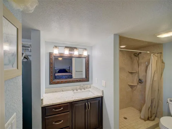 a bathroom with a granite countertop sink mirror and shower
