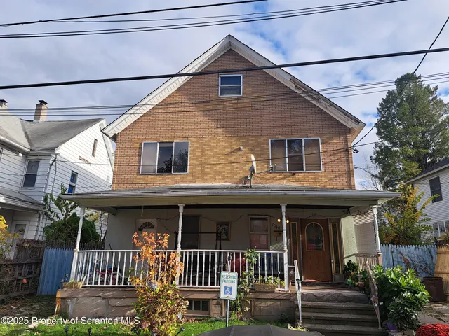 a view of a house with a small yard and wooden fence and plants