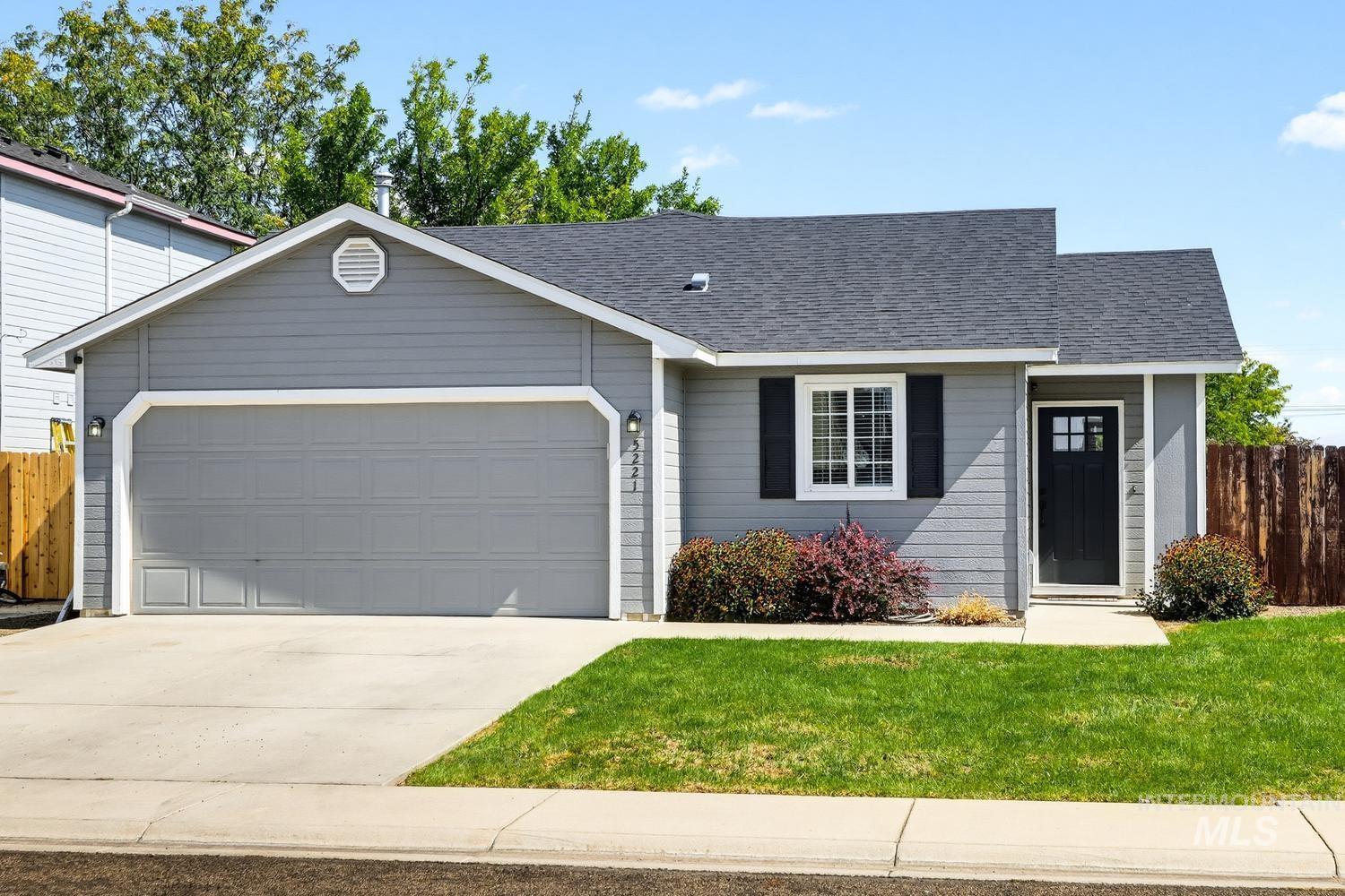 5221 Lockwood Way Caldwell, ID 83607 - Photo 1 of 27 Gray siding exterior with an attached garage, dark asphalt shingle roof, and a front entry door with glass paneling