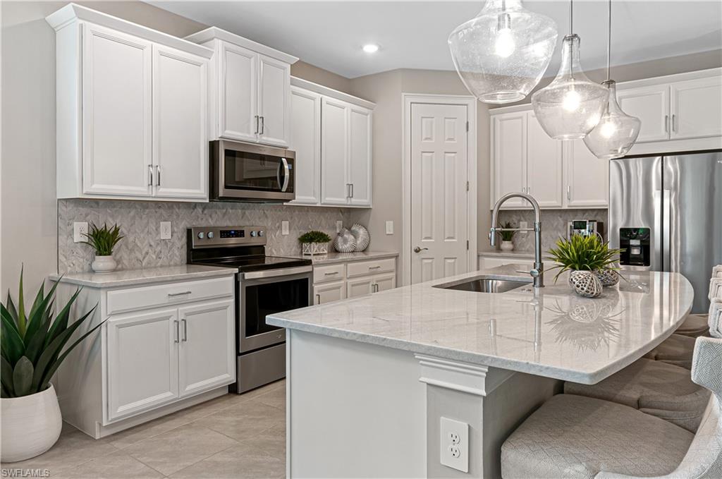 14506 Kelson Circle Naples, FL 34114 - Photo 7 of 25 a kitchen with stainless steel appliances granite countertop a sink a stove and cabinets