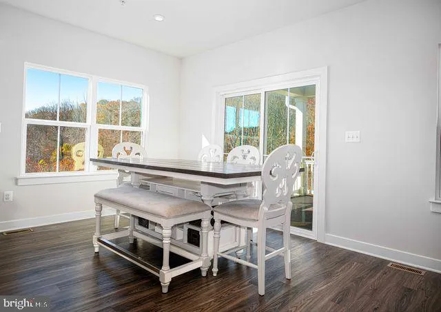 a kitchen with stainless steel appliances granite countertop a table chairs refrigerator and wooden cabinets