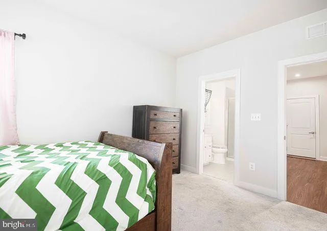 a living room with stainless steel appliances kitchen island granite countertop a refrigerator a stove a oven and white cabinets with wooden floor