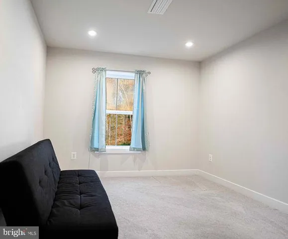 a view of an empty room with a window and a kitchen