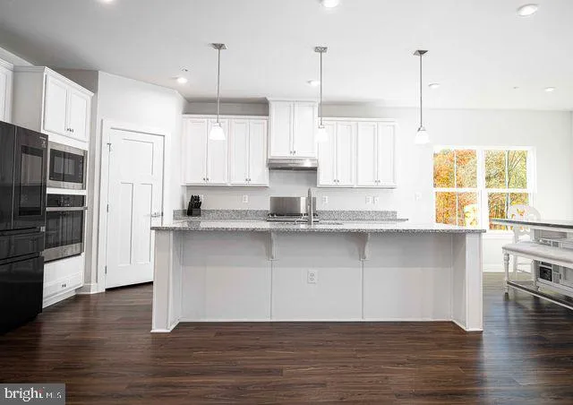 a kitchen with stainless steel appliances granite countertop wooden floors and white cabinets