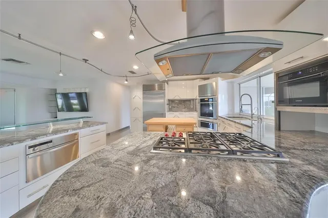 a large kitchen with stainless steel appliances granite countertop a stove and a sink