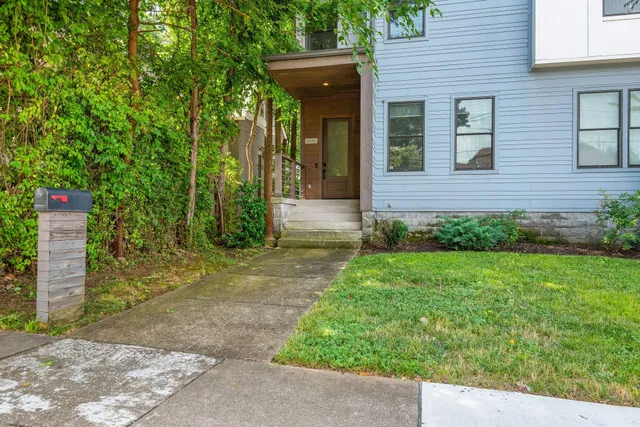 a view of a brick house with a large windows plants and large trees