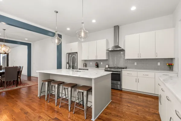 a kitchen with stainless steel appliances granite countertop a table chairs sink and cabinets