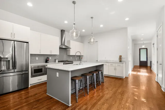 a kitchen with kitchen island a sink stainless steel appliances and wooden floor