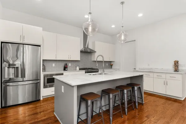a kitchen with stainless steel appliances granite countertop a sink a stove a refrigerator and island with wooden floor