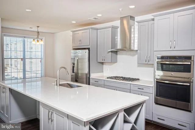 a kitchen with stainless steel appliances a sink a stove a refrigerator cabinets and a counter top space