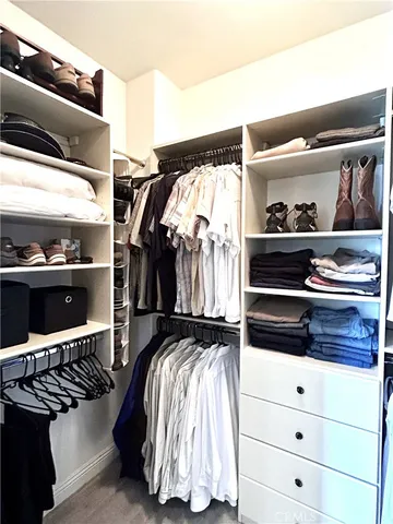 a view of walk in closet with clothes and shoes