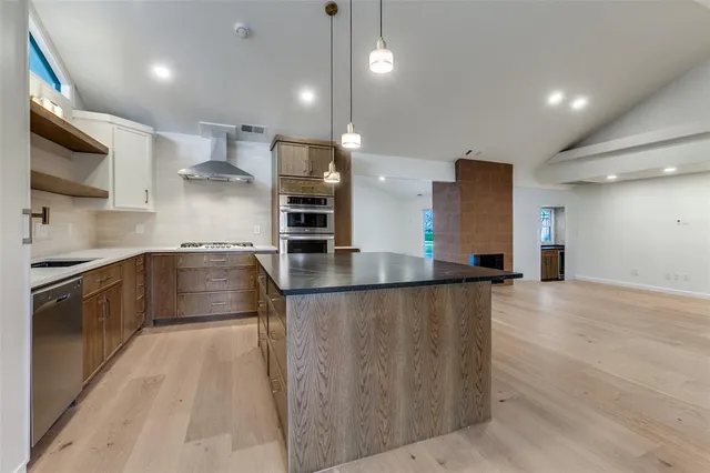 a large kitchen with stainless steel appliances kitchen island granite countertop a stove a sink and a refrigerator