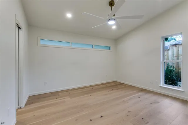 an empty room with wooden floor fan and window