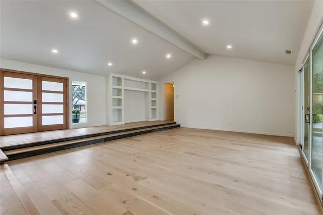 an empty room with wooden floor and window