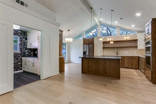 a large kitchen with stainless steel appliances kitchen island a large counter space a sink and a refrigerator