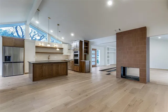 a kitchen with stainless steel appliances kitchen island granite countertop a refrigerator and a stove top oven