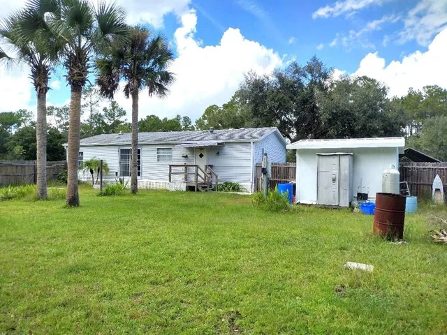 a view of a house with backyard and a tree