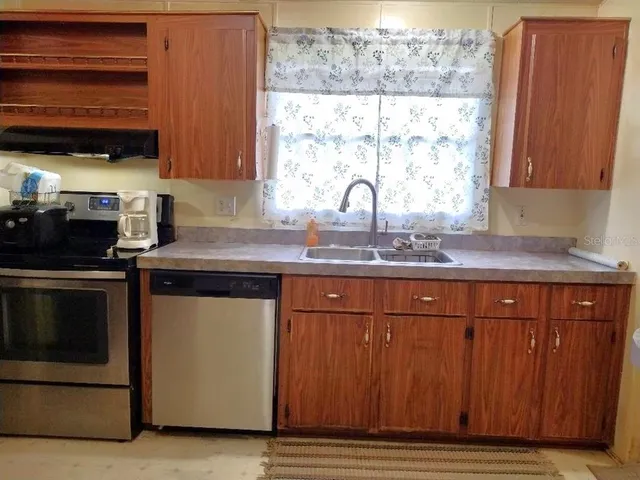 a kitchen with granite countertop wooden cabinets a stove and a window