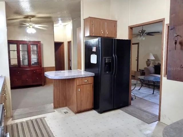 a living room with stainless steel appliances kitchen island granite countertop furniture and a refrigerator