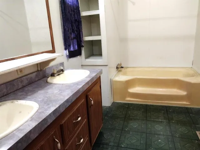 a bathroom with a granite countertop sink and a bathtub